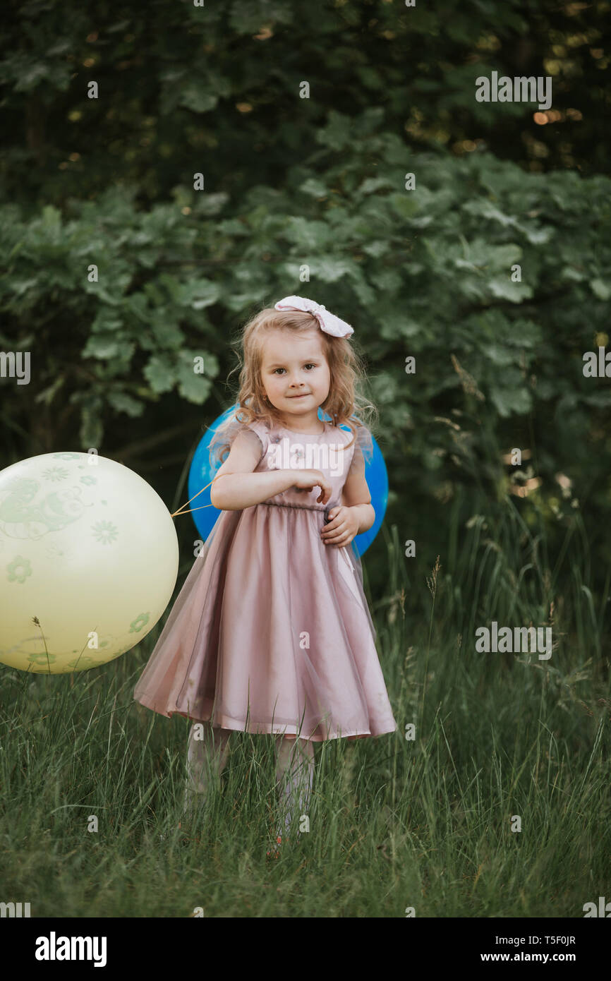 Elegante niña 4-5 años de celebración gran globo vistiendo la moda vestido  rosado en la pradera. Juguetón. Fiesta de cumpleaños. niña con un globo en  el par Fotografía de stock - Alamy