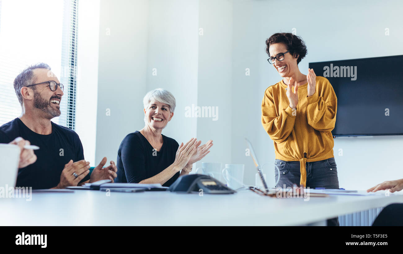 Los empresarios de las palmas después de la exitosa sesión de lluvia de ideas en la sala de juntas. Grupo de hombres y mujeres aplaudiendo tras la reunión productiva. Foto de stock
