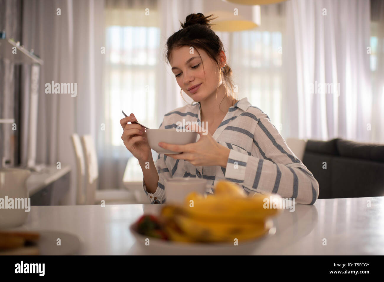 Un retrato de mujer de comer un desayuno saludable en casa en su cocina Foto de stock