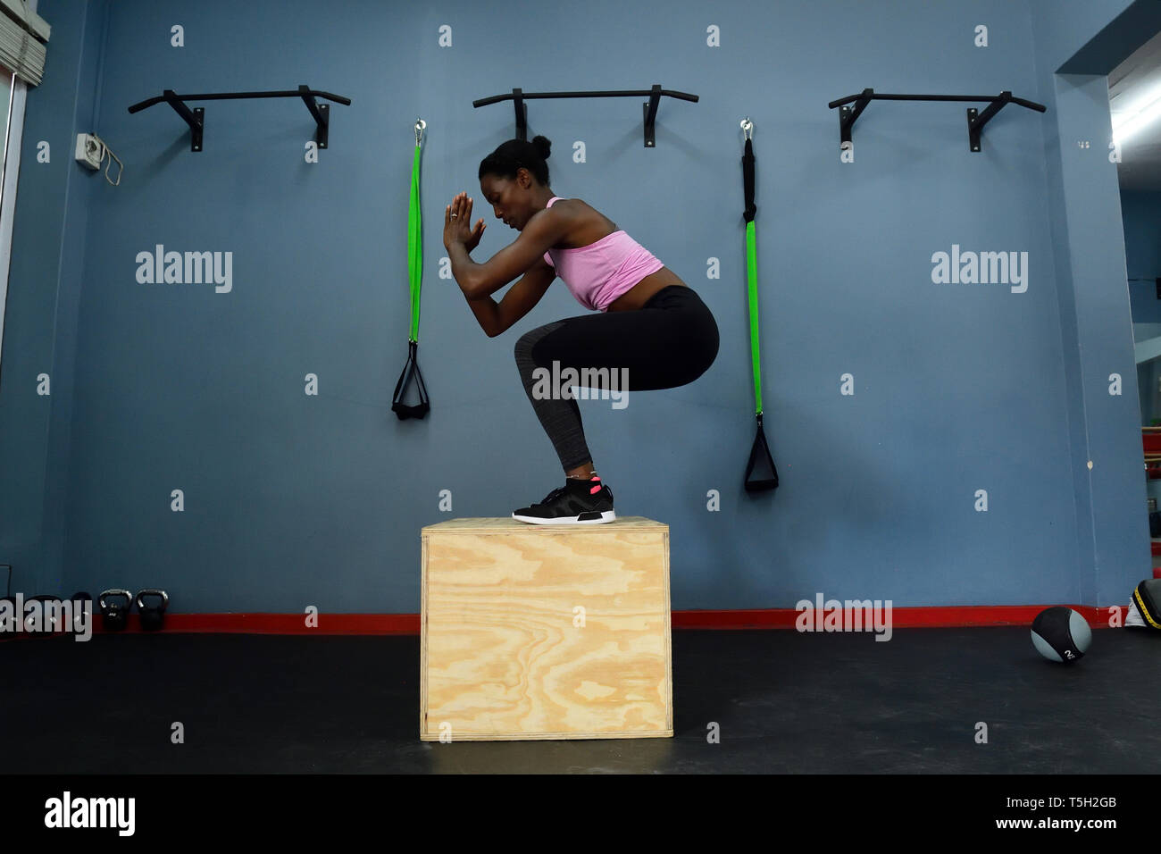 Mujer practicando en un gimnasio haciendo un cuadro saltar Foto de stock
