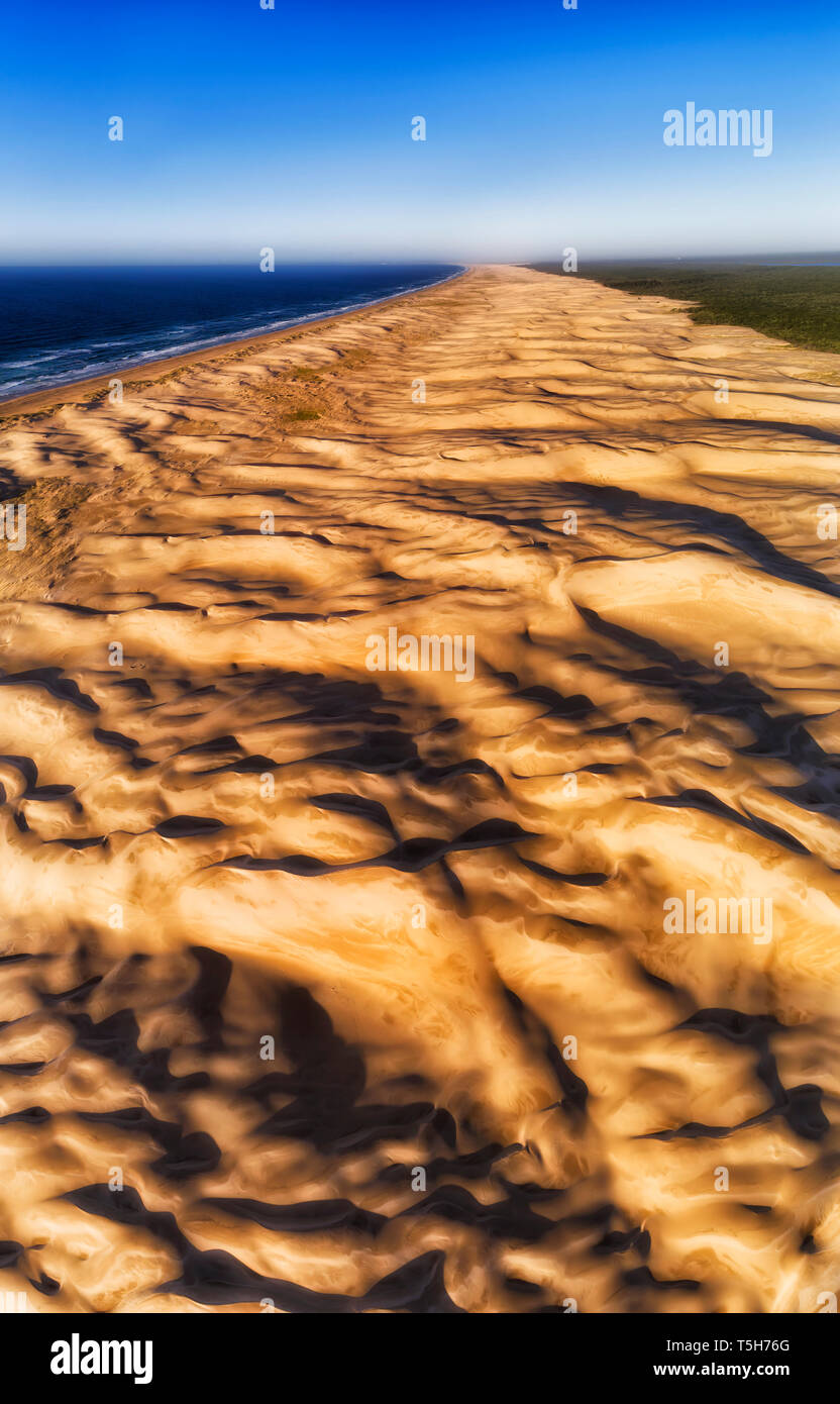 El viento erosiona la superficie de dunas de arena en Stockton Beach Pacific Coast en Australia. Antena elevada panorama vertical de arriba a abajo y distante horizonte Foto de stock