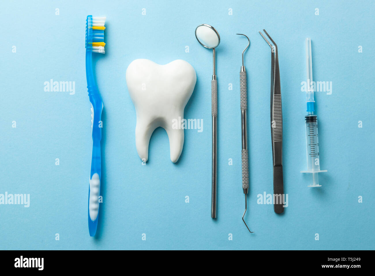 Instrumentos dentales y dientes sobre fondo azul. Tratamiento dental.  Herramientas de dentista, espejo, pinzas de gancho, jeringa y cepillo de  dientes Fotografía de stock - Alamy
