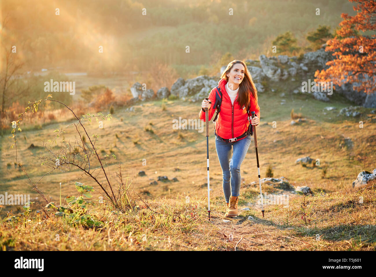 Feliz mujer caminando en el camino en una excursión en las montañas Foto de stock