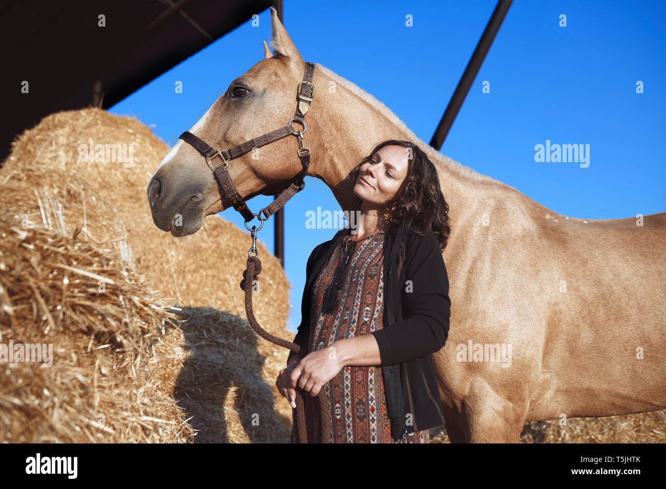 La mujer embarazada con el caballo en el granero de heno Foto de stock