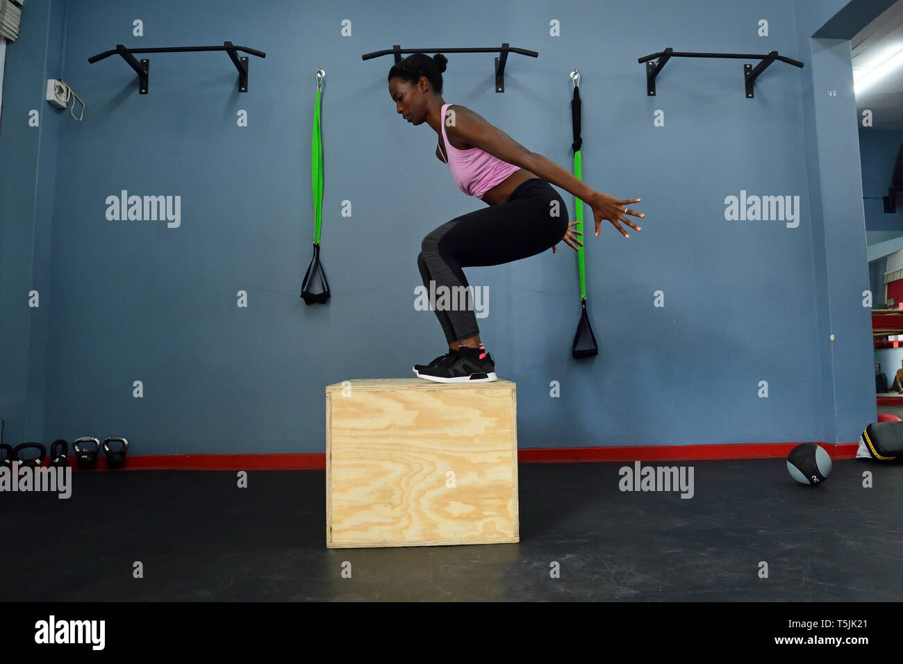 Mujer practicando en un gimnasio haciendo un cuadro saltar Foto de stock