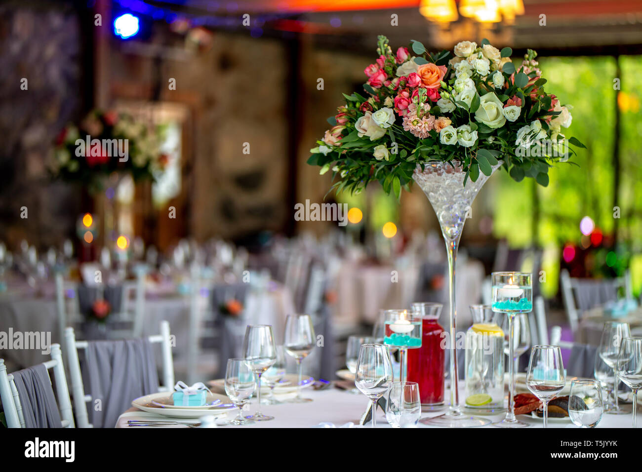 Decoración de la mesa de bodas. Precioso ramo de flores en un jarrón sobre la mesa, junto con platos, vasos y cajas de regalo. Bouquet de flores, vasos, gif Foto de stock
