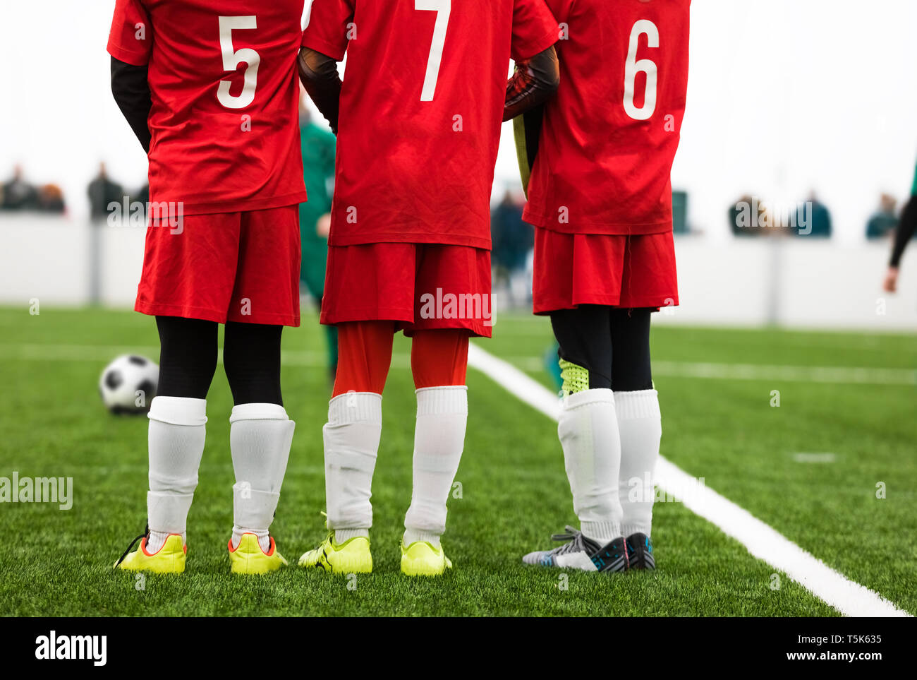Jugadores fútbol Junior de pie en una pared. Free Kick situación el de fútbol. Los jugadores vestidos de rojo Camiseta de camisetas con números en la espalda. Así