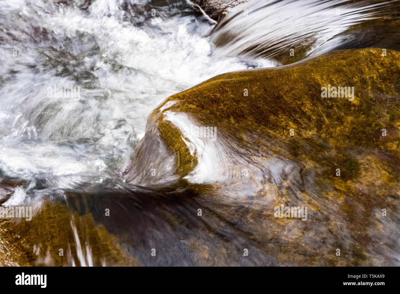 El agua haciéndola rodar sobre las piedras en un arroyo de montaña Foto de stock