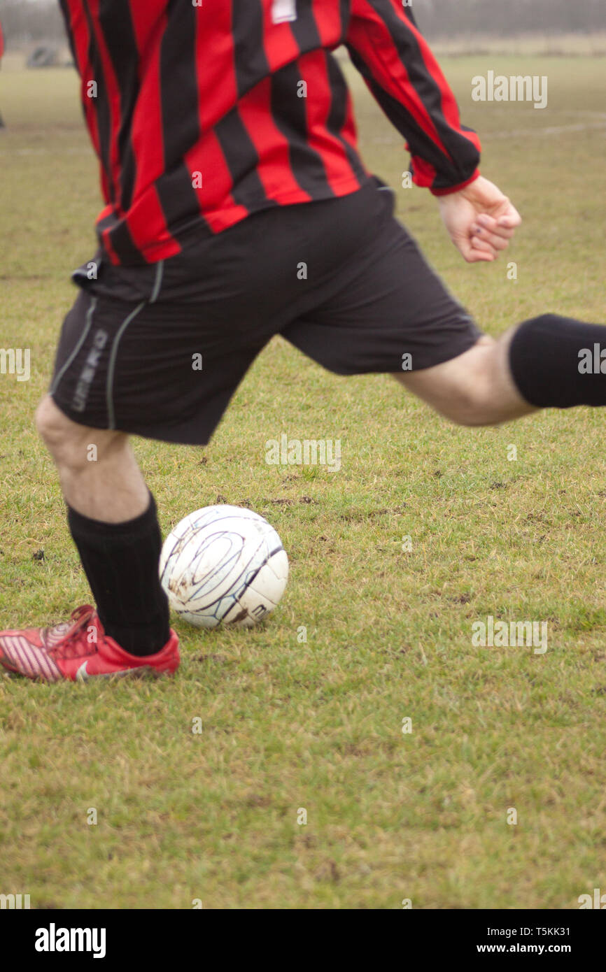Cerca de un hombre a punto de golpear un balón de fútbol Foto de stock