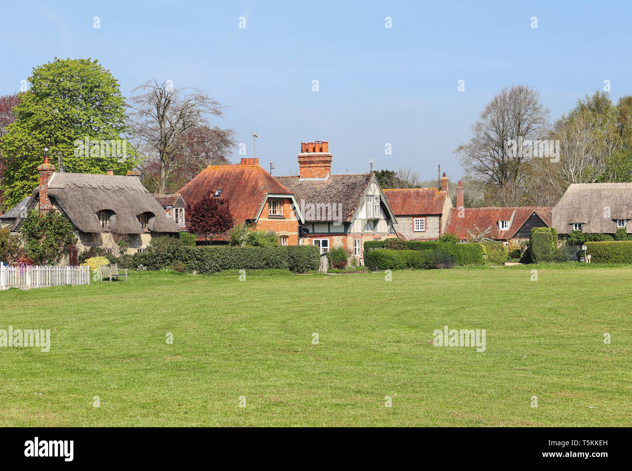 Una fila de casas de pueblo tradicional inglés en Oxfordshire con village green en primer plano Foto de stock