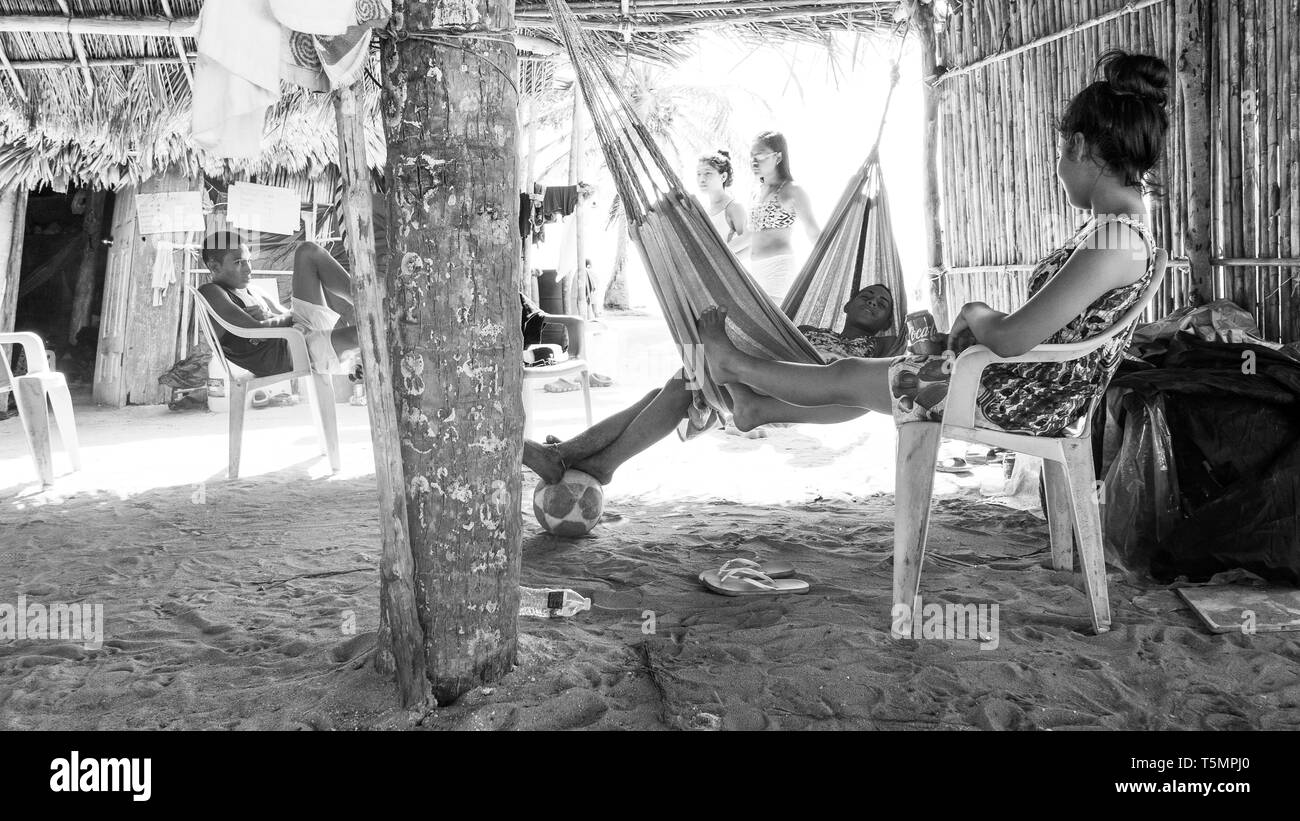 Guna (kuna) miembros tribales comunal grande relajarse bajo una choza hecha con hojas de palmera, viendo como los turistas visitan su isla y comprar Molas Foto de stock