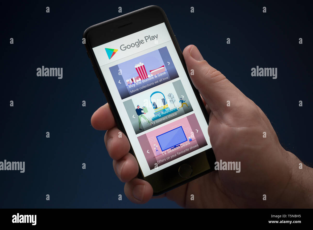 Un hombre mira el iPhone que muestra el logotipo de Google Play (uso Editorial solamente). Foto de stock