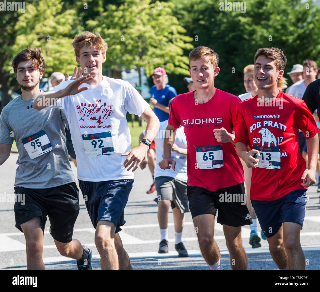 Bay Shore, NUEVA YORK, EEUU, 16 de junio de 2018: cuatro corredoras onda a cámara mientras racing la carrera por PWS recaudador de fondos en las carreteras. Foto de stock