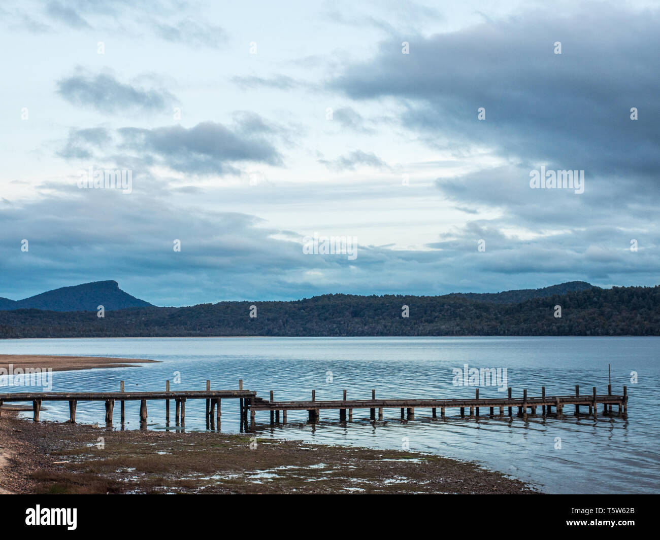 Wharf, agua tranquila que refleja el cielo nocturno, lejanas colinas oscuras, una noche de otoño, el lago Hauroko, Parque Nacional Fiordland Foto de stock