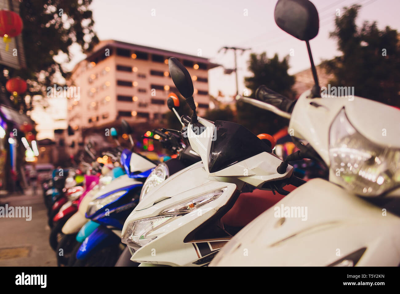 Moto scooter, motocicleta estacionada en la fila en las calles de la ciudad. Cerca de la rueda. Foto de stock
