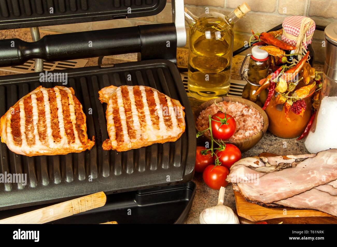https://c8.alamy.com/compes/t61nrk/grill-steak-en-una-estufa-electrica-cuello-de-cerdo-frito-sobre-pequenos-grill-electrico-cocinar-en-casa-barbacoa-saludable-catering-para-los-amigos-grill-electrico-t61nrk.jpg