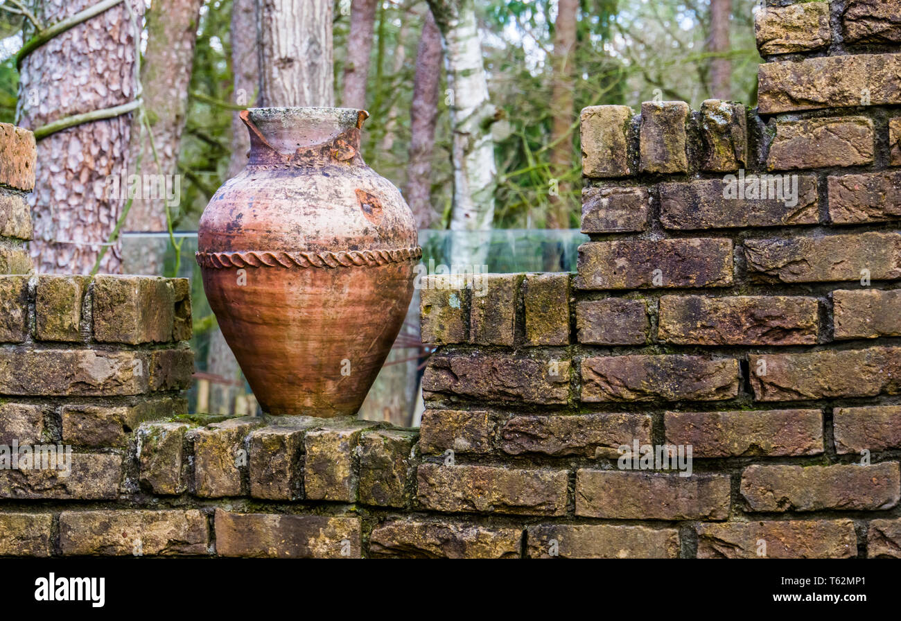 Antiguo jarrón romano astillada sobre una pared de ladrillos, la arquitectura y las decoraciones de jardín al aire libre Foto de stock