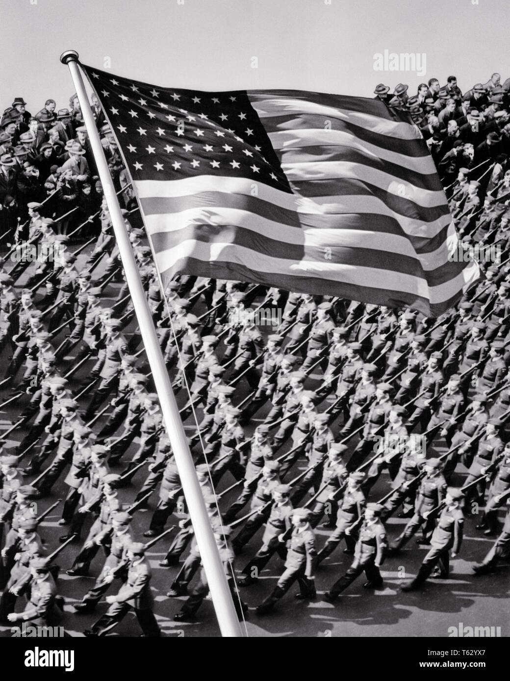 1940, PATRÓN DE LA CIUDAD DE NUEVA YORK hombres marchando tropas con bandera de EE.UU. 48 estrellas superpuestas en primer plano - q42140 CPC001 HARS ESPIRITUALIDAD B&W LIBERTAD éxito ángulo alto fuerza victoria valentía emoción liderazgo potente GOTHAM GUERRAS MUNDIALES DIRECCIÓN ORGULLO GUERRA MUNDIAL LA SEGUNDA GUERRA MUNDIAL LA II GUERRA MUNDIAL EN NYC ocupaciones de autoridad política tropas uniformes elegantes ciudades NUEVA YORK CONCEPTUAL DE LA II GUERRA MUNDIAL 48 ESTRELLAS DE HONOR DE LA CIUDAD DE NUEVA YORK PRECISION ROJO BLANCO Y AZUL, LAS ESTRELLAS Y LAS TIRAS EN BLANCO Y NEGRO LUGARES DE PRIMER PLANO superpuesto a la antigua usanza Foto de stock