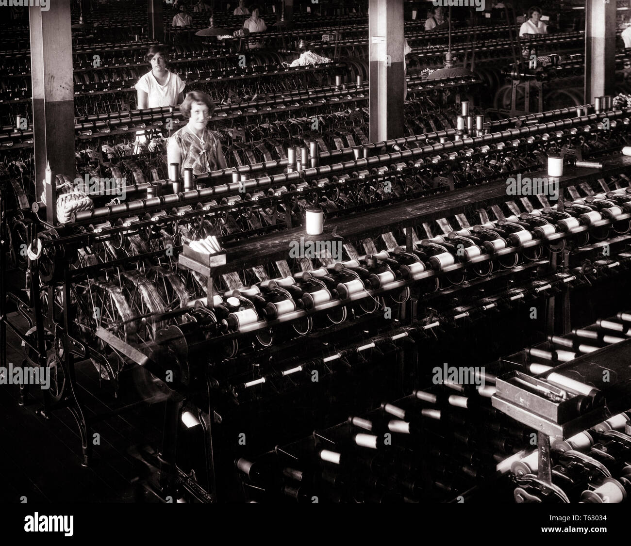 1920 dos mujeres trabajadores textiles mirando a la cámara en grandes máquinas de hilado de seda INTERIOR INDUSTRIAL ARROJANDO FACTORY - q74727 CPC001 HARS arrojando centro industrial SEGURIDAD HISTORIA LIFESTYLE MUJERES SPINNING EMPLEOS PERSONA ESTADOS UNIDOS longitud media estimadas PERSONAS TELA CRECIDO RIESGO B&W TEXTIL TRISTEZA NORTEAMÉRICA CONTACTO OCULAR DECORACIÓN Decoración habilidades NORTEAMERICANO SUEÑOS OCUPACIÓN MATERIAL HABILIDADES CENTRO URBANO MÁQUINAS PA NORESTE DE KEYSTONE ocupaciones laborales en la región del Atlántico Medio región del Atlántico medio del Commonwealth COSTA ORIENTAL CONCEPTUAL ESCAPAR ESTADO TRAPEZOIDAL TEXTILES BOBINAS MEDIADOS DE ADULTO Foto de stock