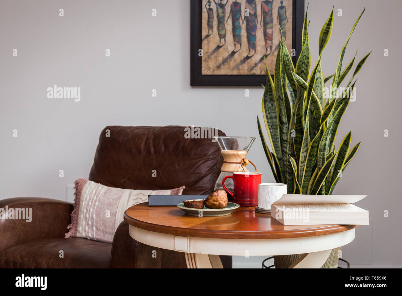 Una moderna sala de estar y mesa de café con una taza de café, libro, tabletas y un panecillo. Foto de stock