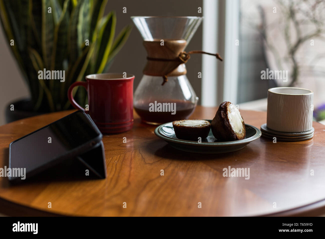 Una moderna sala de estar y mesa de café con una taza de café, libro, tabletas y un panecillo. Foto de stock