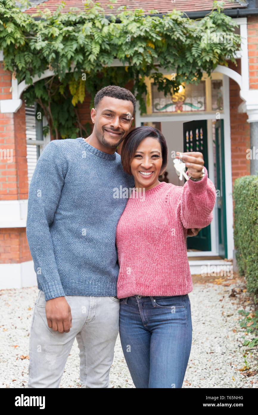 Retrato feliz pareja sosteniendo llaves de casa fuera de casa nueva Foto de stock