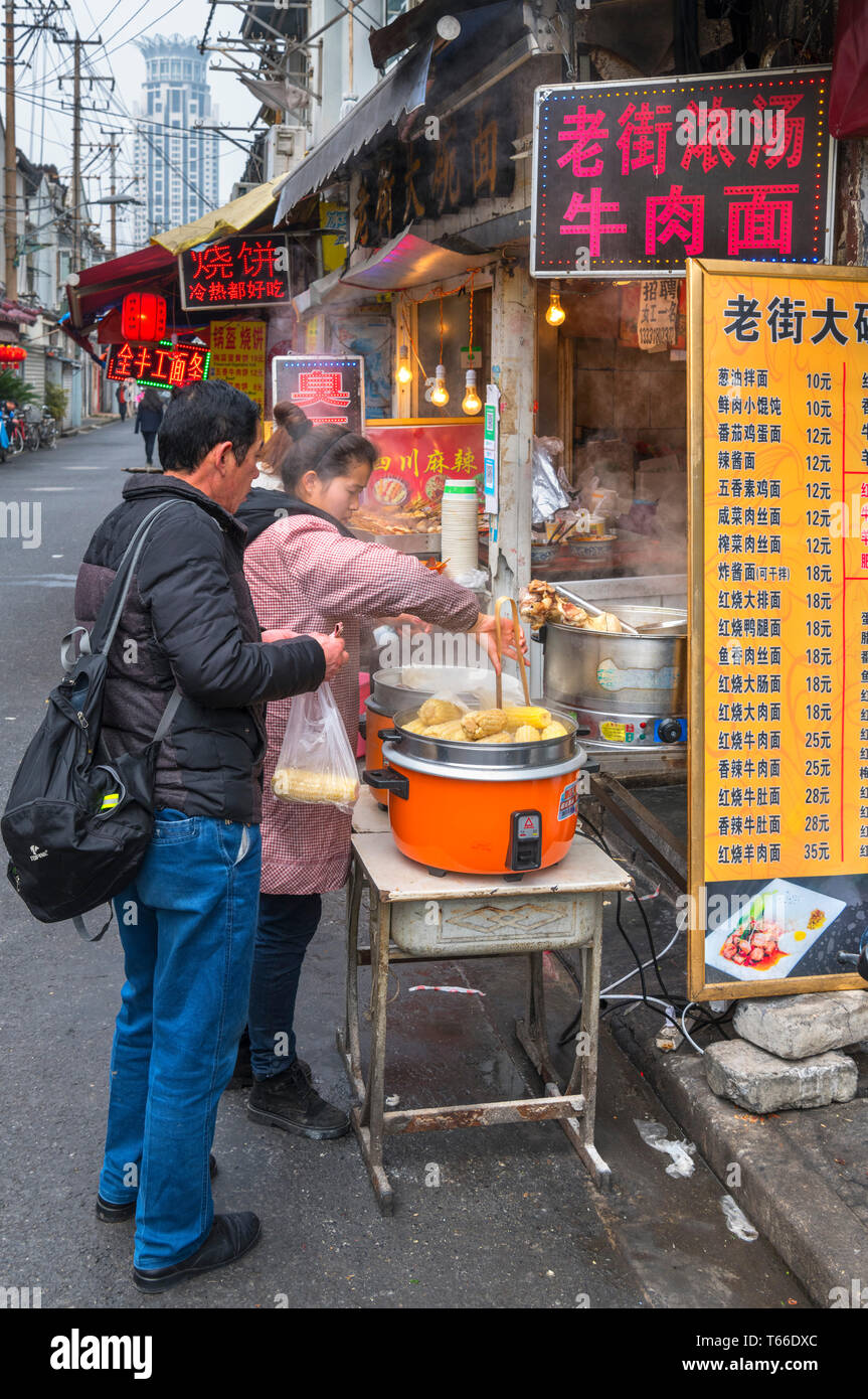Shanghai, comida de la calle. Par la compra de alimentos en un puesto de comida tradicional en la Ciudad Vieja, Shanghai, China Foto de stock