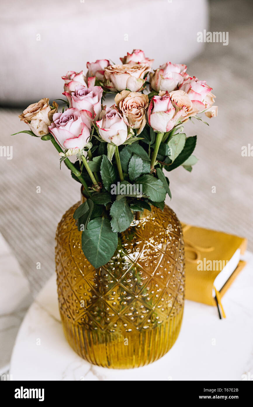Un bello ramo de rosas en un vaso de vidrio sobre una mesa en una sala de un día. Concepto de decoración del hogar. Las Hermosas flores en la sala de estar. Foto de stock
