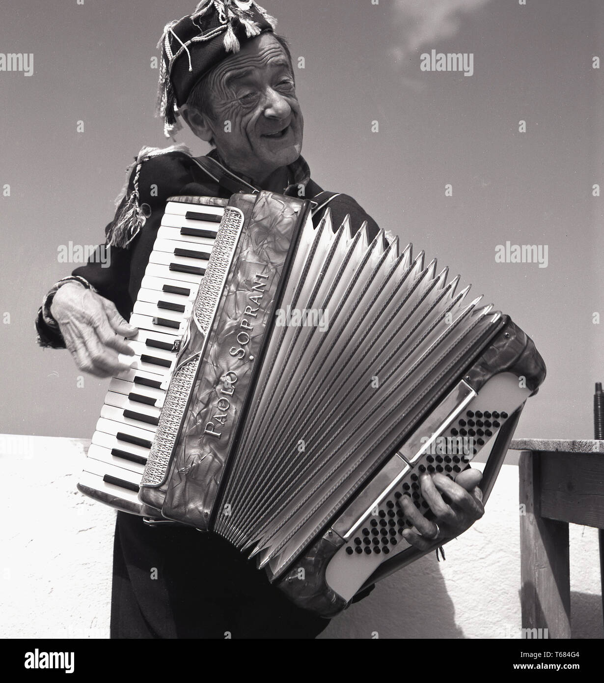 1950, histórico, en la calle, músico o ejecutante, un anciano fuera de  tocar un instrumento musical, un acordeón, Italia. Él está jugando a Paolo  Soprani acordeón de piano con un teclado musical.