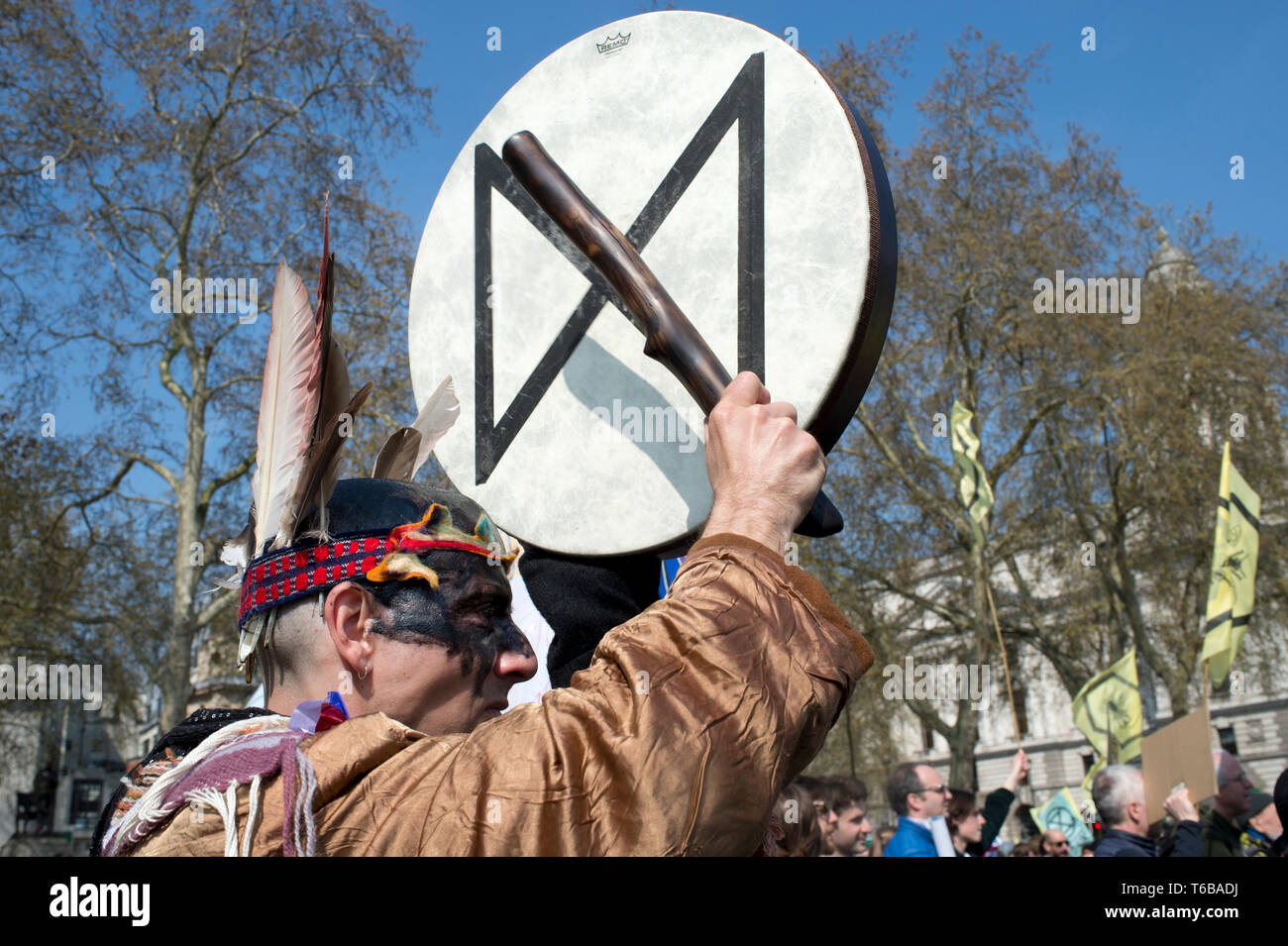 Extinción de rebelión, de protesta en Londres . La Plaza del Parlamento. Un hombre con óleo negro-como la pintura en su rostro late un tambor con la XR símbolo en ella. Foto de stock