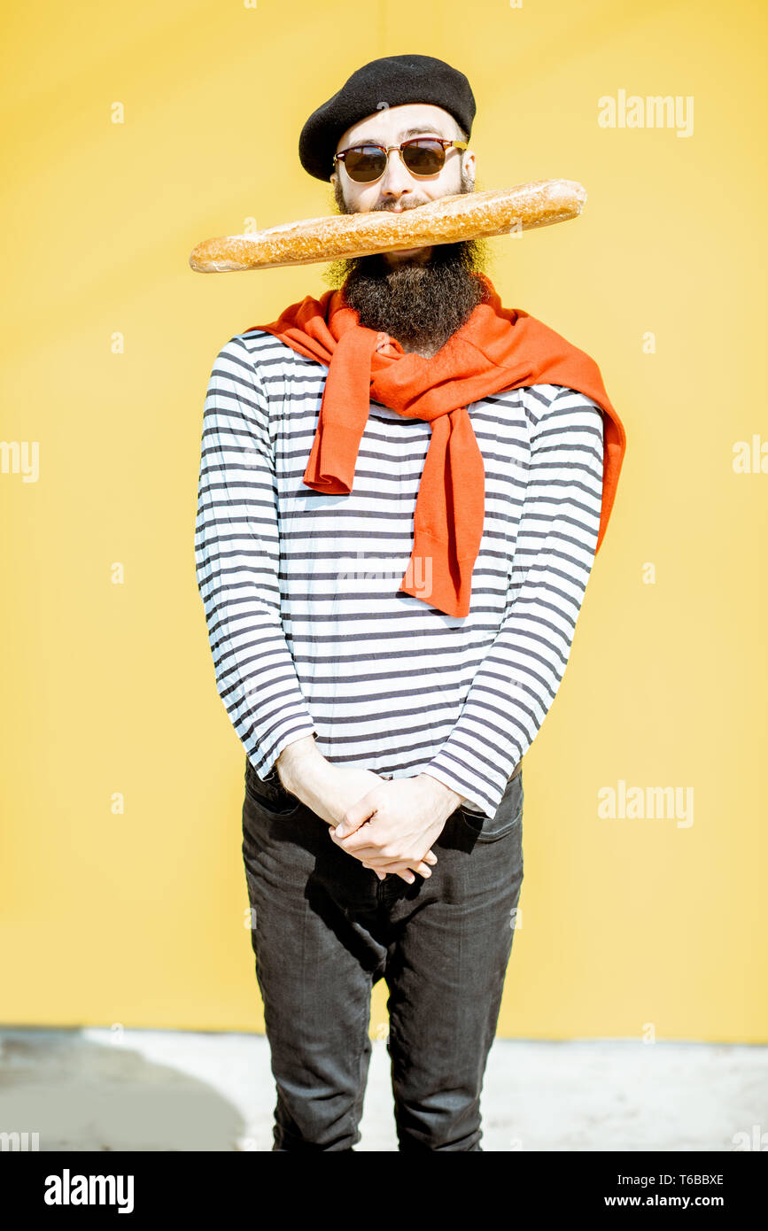 Retrato de un hombre vestido de estilo con camisa a rayas, sombrero y pañuelo rojo sobre fondo amarillo Fotografía de -