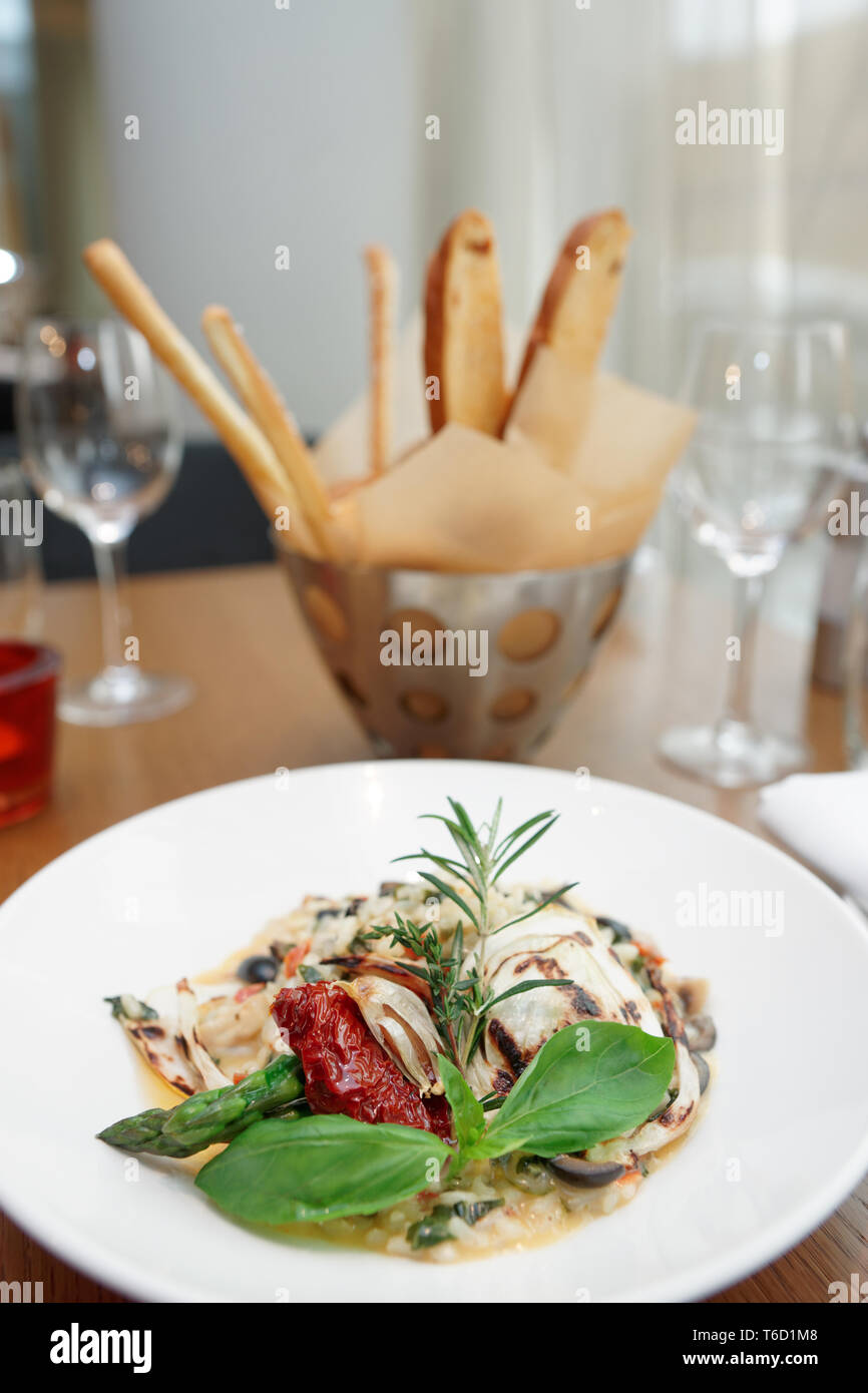 Risotto con tomates secados al sol y hierbas en mesa de restaurante Foto de stock