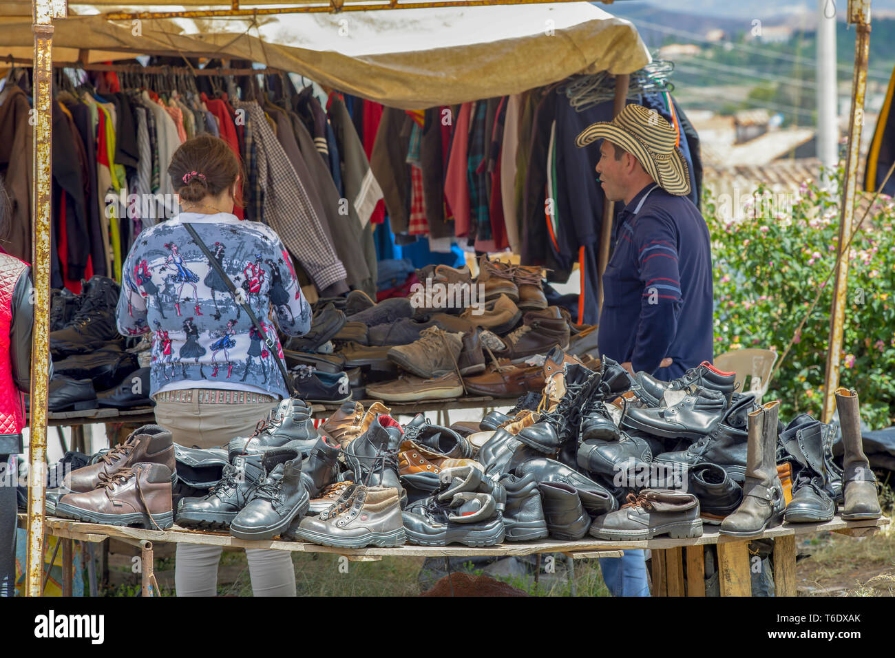 Un hombre atiende a un cliente en su calzado y ropa usada calar en el  tradicional mercado local de Villa de Leyva, Colombia Fotografía de stock -  Alamy