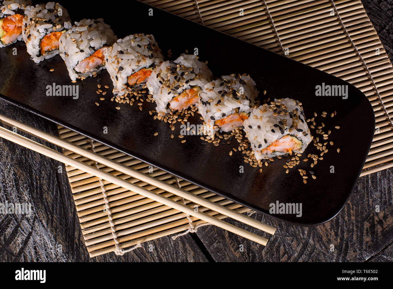 Cortar sushi roll en plato negro Foto de stock
