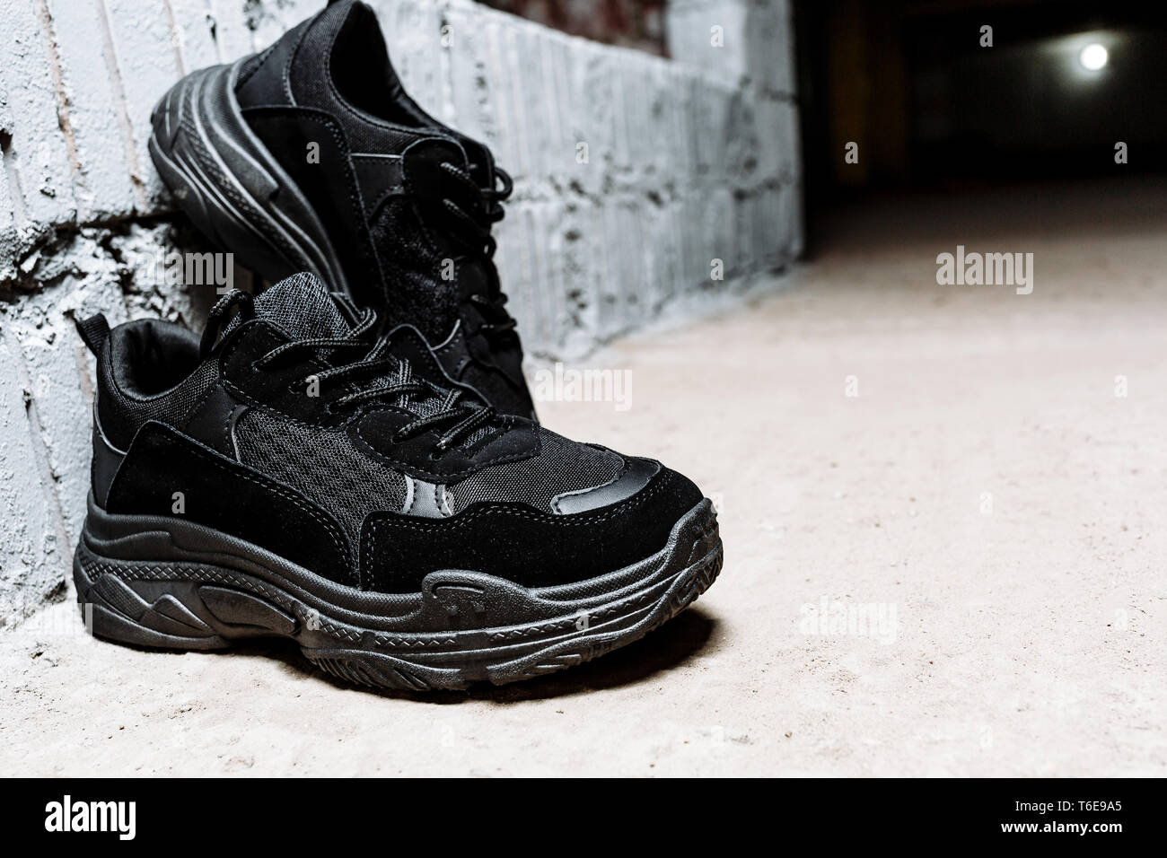 Par de zapatillas negras con suela gruesa en el suelo de cemento con el  telón de fondo de la pared de ladrillo blanco Fotografía de stock - Alamy