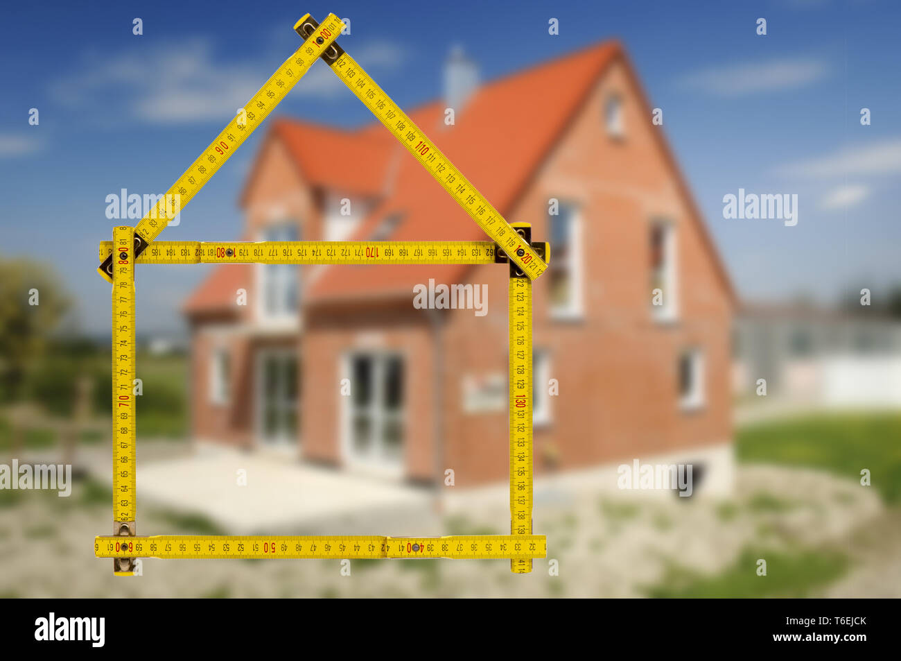 Shell de casa en construcción con regla de plegado en la mano del agente de propiedades inmobiliarias Foto de stock