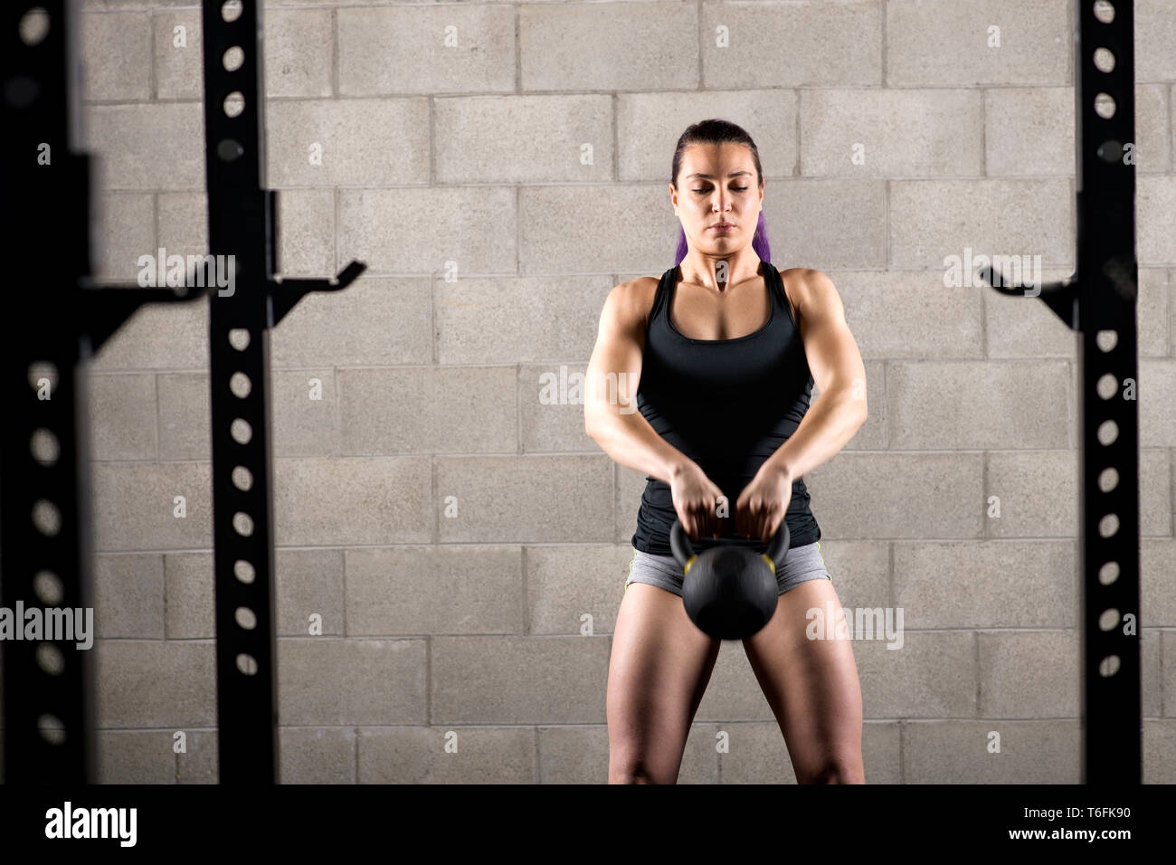 Joven que trabaja con un kettlebell haciendo un pull up levantando