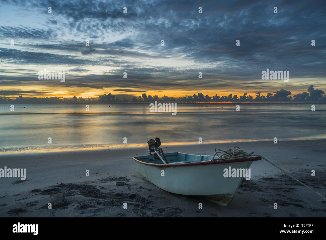 Un hermoso amanecer tropical con un barco en la playa Foto de stock