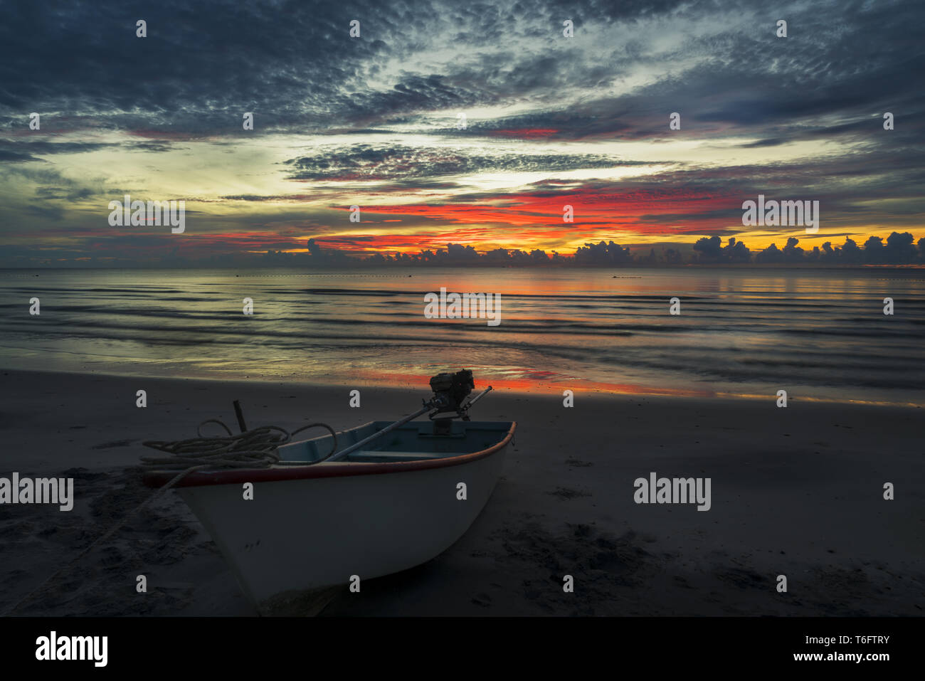 Un hermoso amanecer sobre un tópico de playa con un barco Foto de stock
