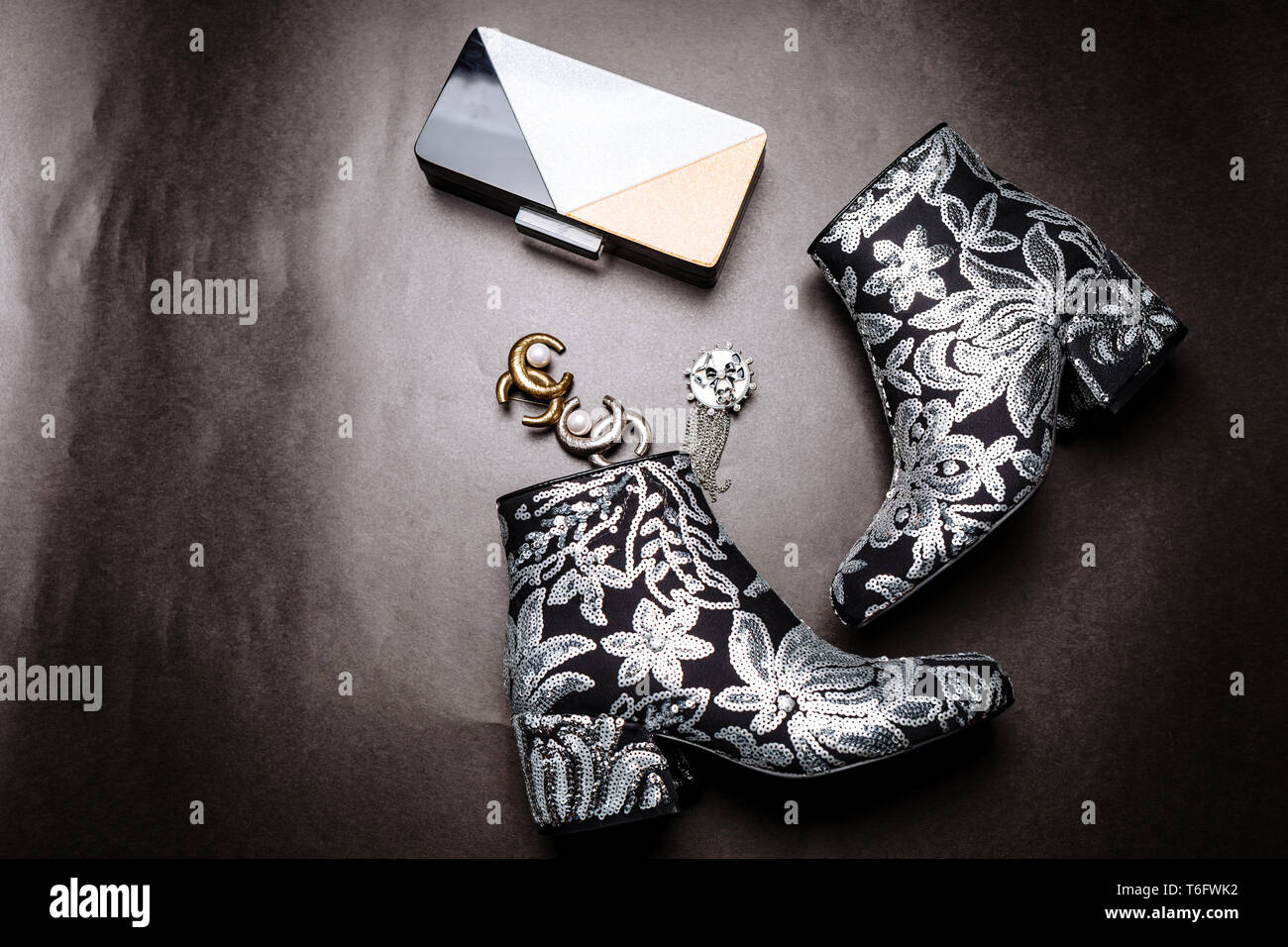 Moda botines con tacón decorado flores bordadas lentejuelas de plata y un embrague de metal y broches en un papel gris Fotografía de stock - Alamy