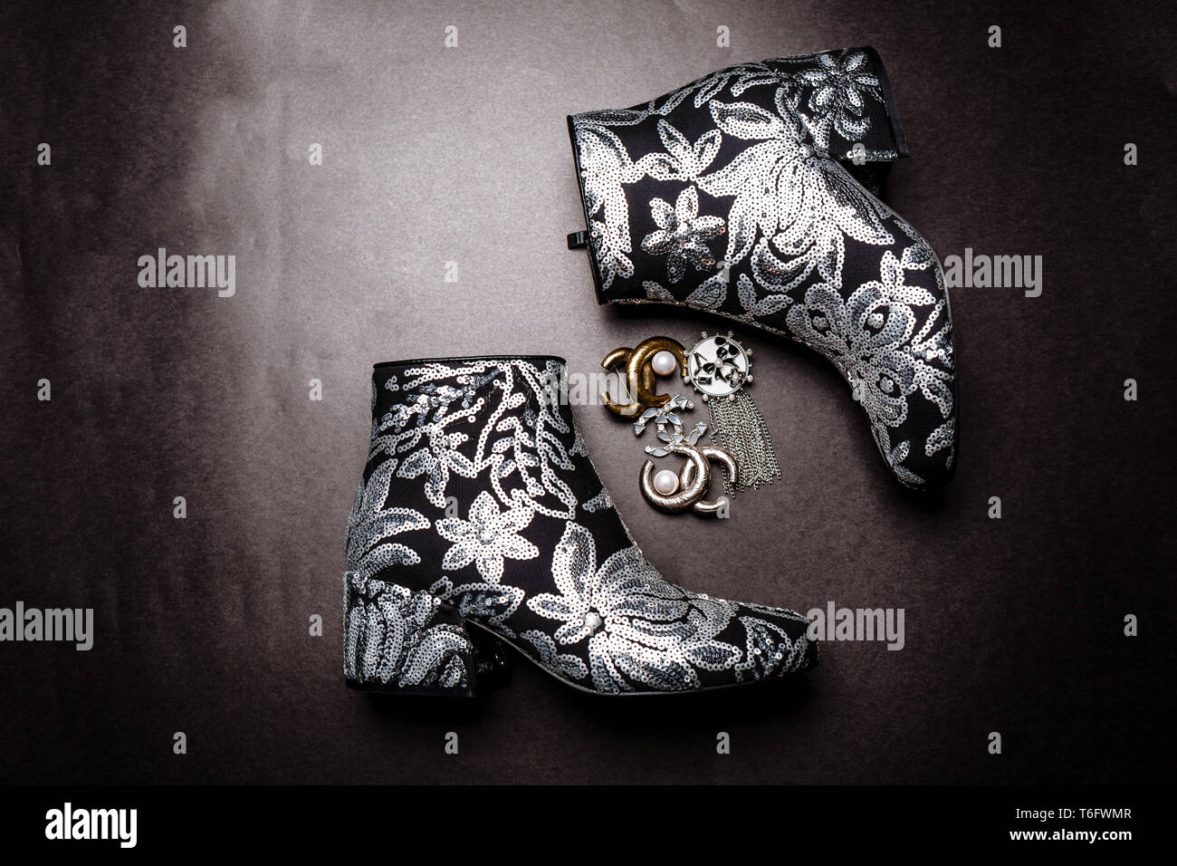 Moda negro botines de tacón grueso decorado con flores bordadas con  lentejuelas de plata y broches sobre un fondo de papel de color gris  Fotografía de stock - Alamy