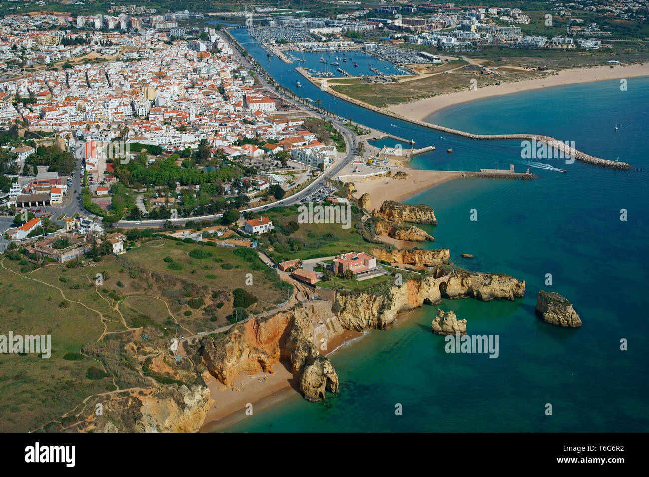 VISTA AÉREA. Ciudad de Lagos y su espectacular costa irregular. Algarve, Portugal. Foto de stock