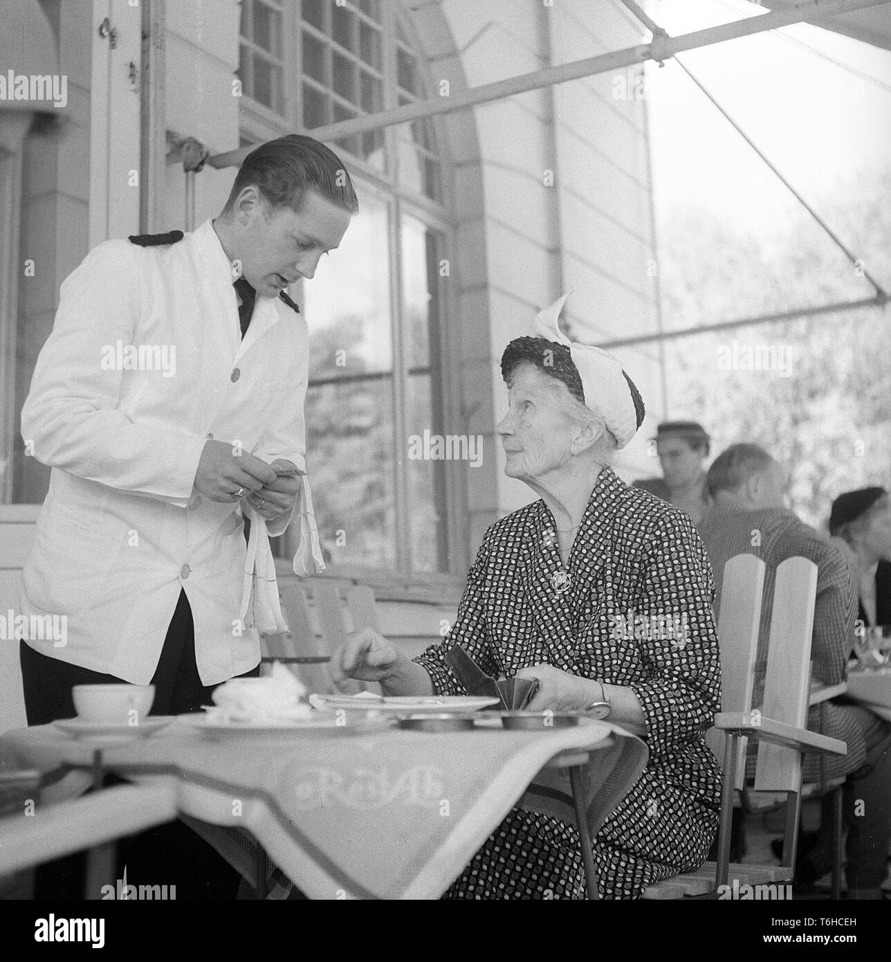 Restaurante 1950. Una anciana es tener una conversación con el camarero al liquidar la factura. Suecia. Foto Kristoffersson BX30-6. Suecia 1956 Foto de stock