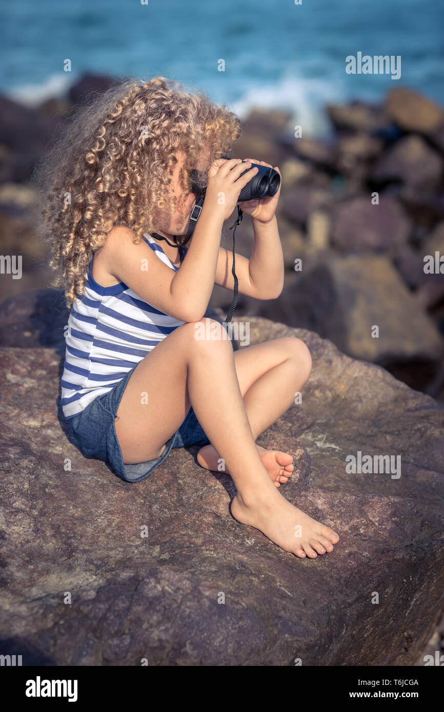 Little Girl mirar muy lejos con binoculares Foto de stock