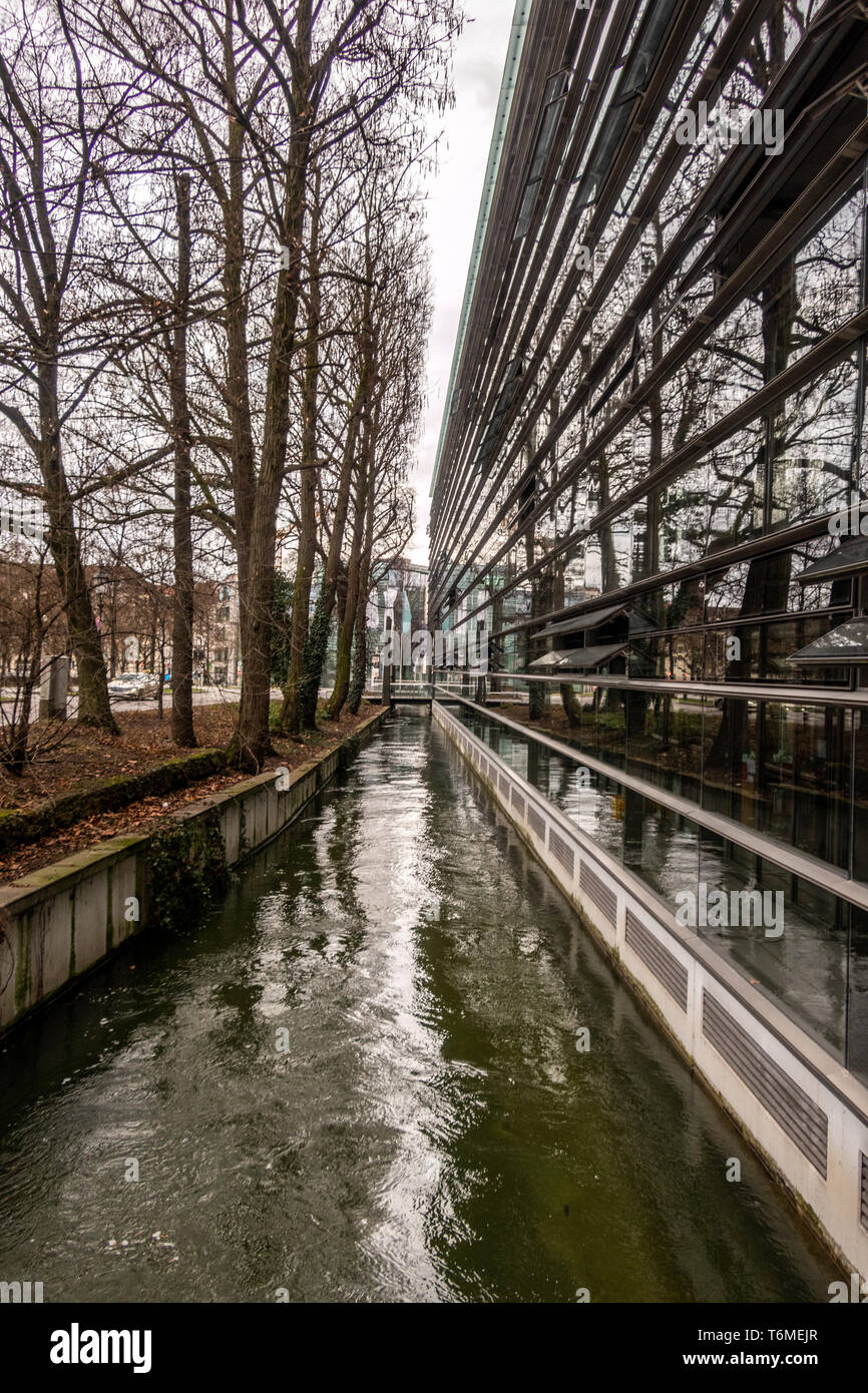 El canal Stadtgrabenbach Westlicher, reflejadas en las oficinas del Instituto Max Planck para la innovación y la competencia. Munich, Alemania Foto de stock