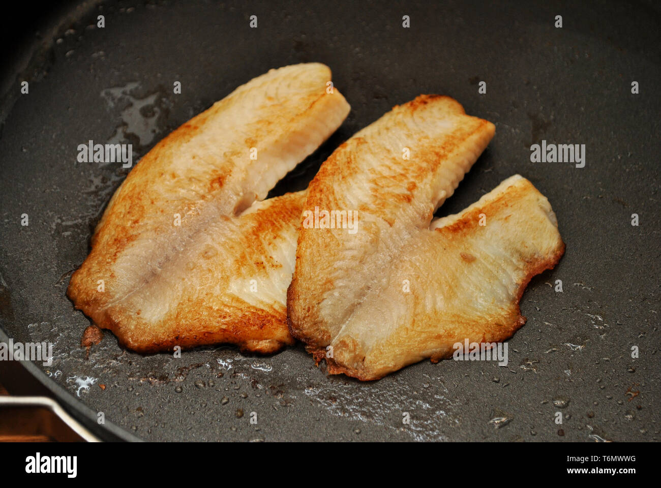 Freír los filetes de pescado blanco en una sartén Foto de stock
