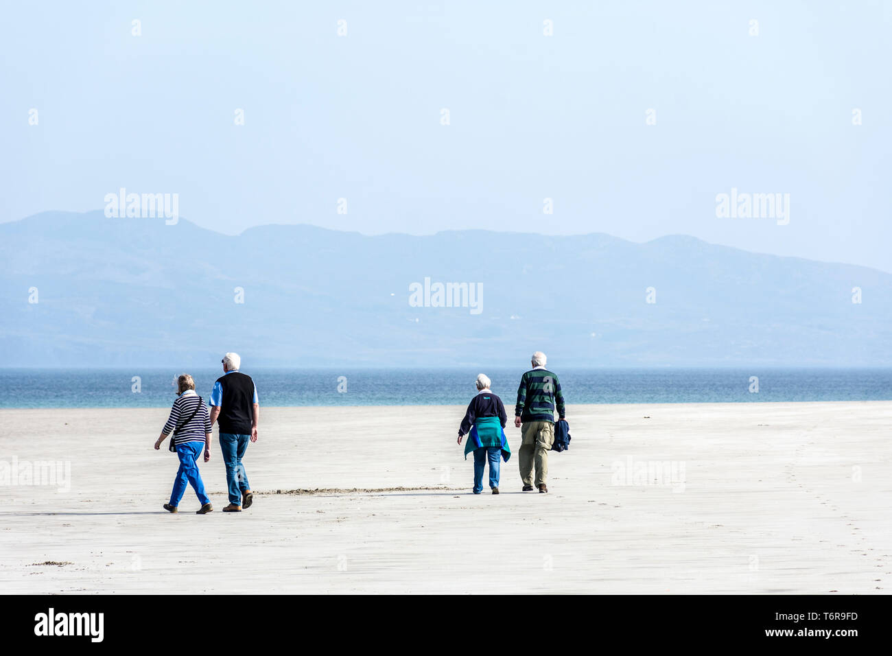 Dos parejas senior en la playa caminando, en el condado de Donegal, Irlanda Foto de stock
