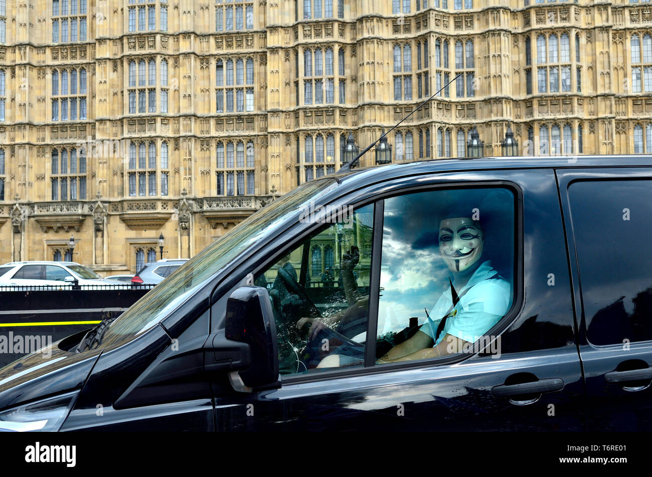 Londres, Inglaterra, Reino Unido. Hombre que llevaba una máscara de V de Vendetta en el asiento del pasajero de una furgoneta, pasando por las Casas del Parlamento Foto de stock