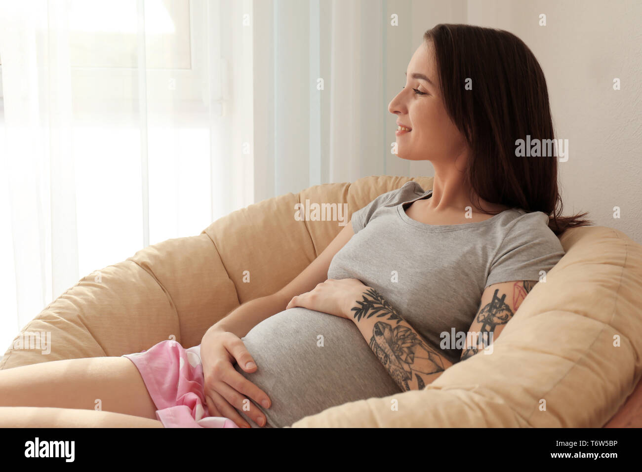 Hermosa mujer embarazada sentada en un sillón en la mañana Fotografía de  stock - Alamy