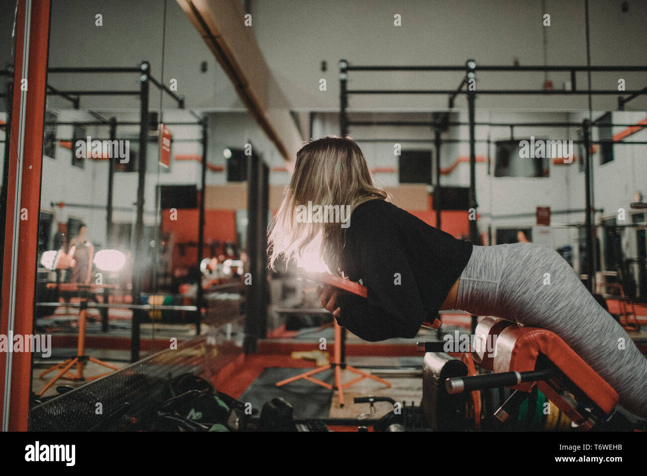 Mujer atractiva el levantamiento de pesos en Hyper Extension Bench en el gimnasio Foto de stock